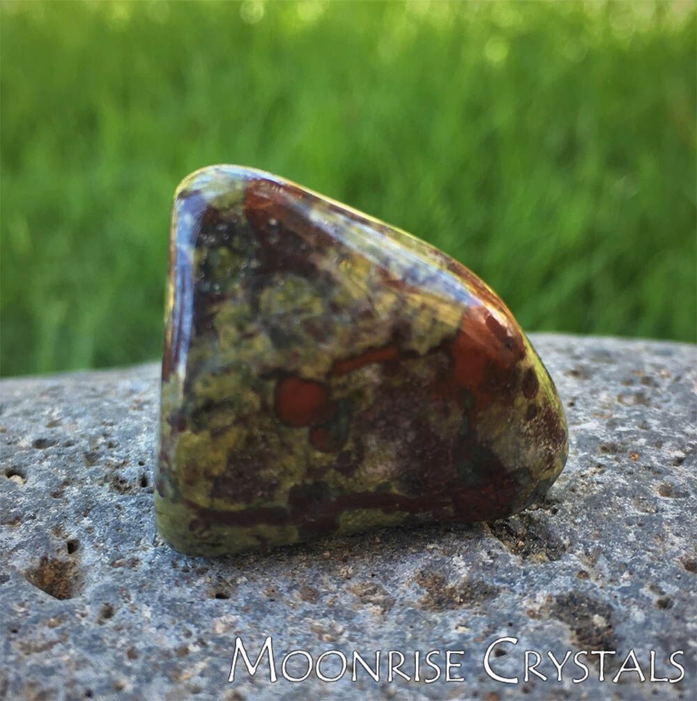 Tumbled Dragonstone on a rock with grass in the background