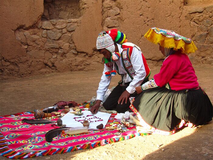 Peruvian people in indigenous clothing doing a ritual on a blanket