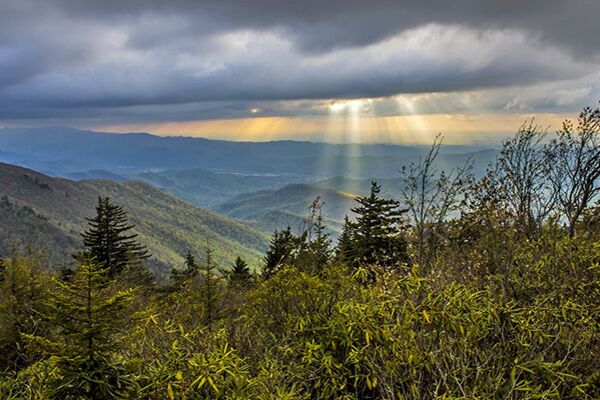 Sunlight streaming through the clouds over the green Unakas mountains