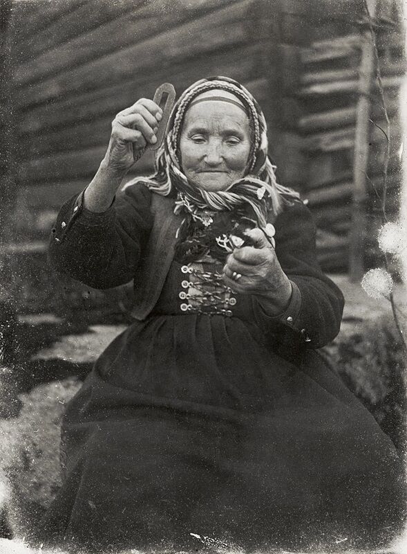 Black and white photo of an old woman using flint and iron to start a fire