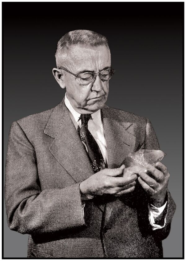 Vonsen Black and white portrait of Magnus Vonsen, wearing a suit and glasses, studying a rock