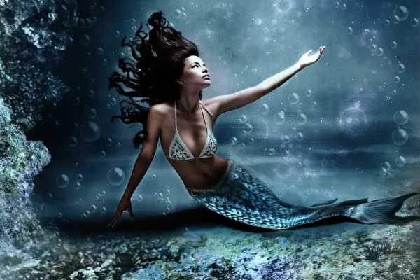 Mermaid underwater with a blue tail and dark hair