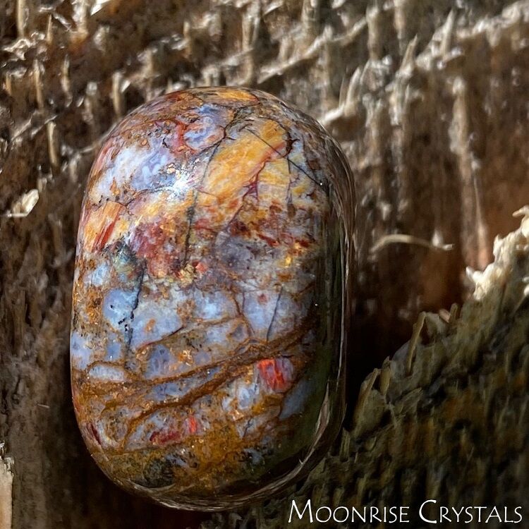 Close up of tumbled Pietersite against a wooden background