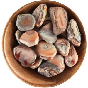 Bowl of tumbled Botswana Agate. Irregular shapes, smoothly polished, with warm hues of pink, orange, and brown, as well as cooler hues of purpleish-gray
