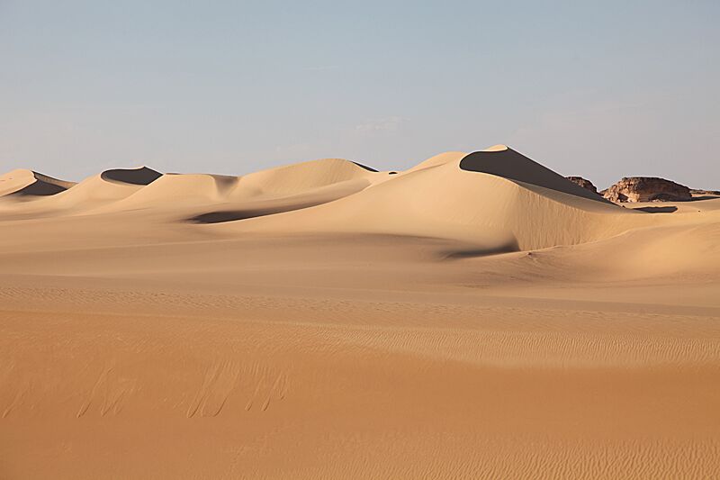Tan sand dunes under a grey sky